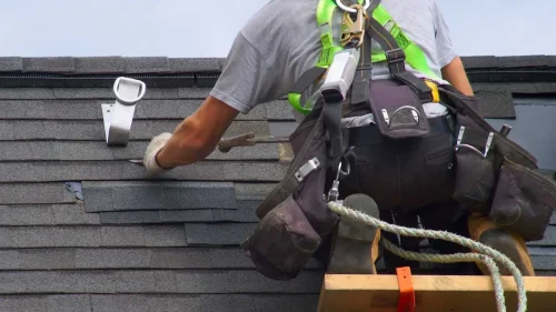 Roofer inspecting a roof over 15 years old to evaluate repair or replacement