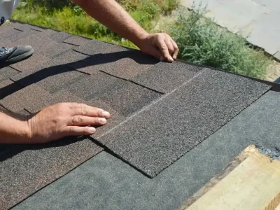 Roofer inspecting a residential roof for damage after a windstorm