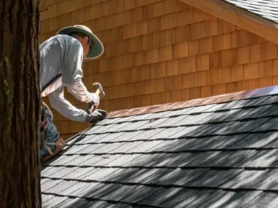 Roofer installing flashing along a roof edge to prevent water intrusion