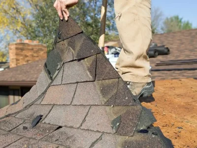 Roofer lifting shingles showing minor roof issue